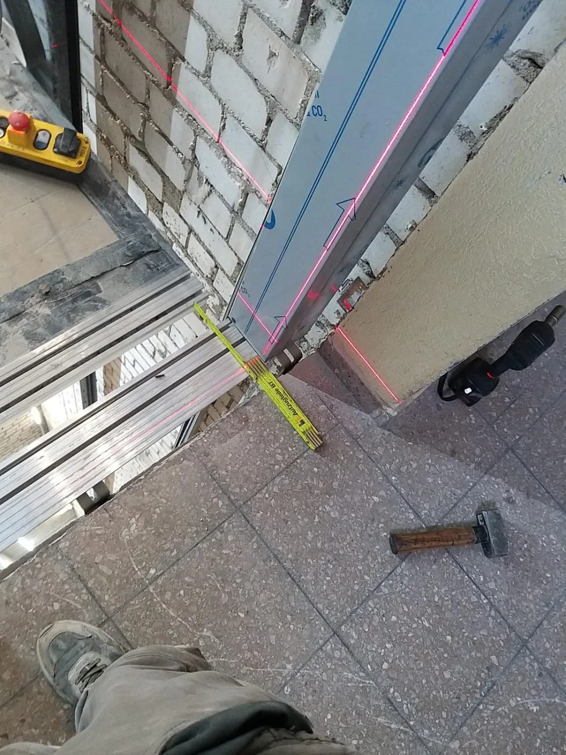 Lasereinmessung an einer Schachttüröffnung mit Laserlinien, Zollstock und Werkzeug
