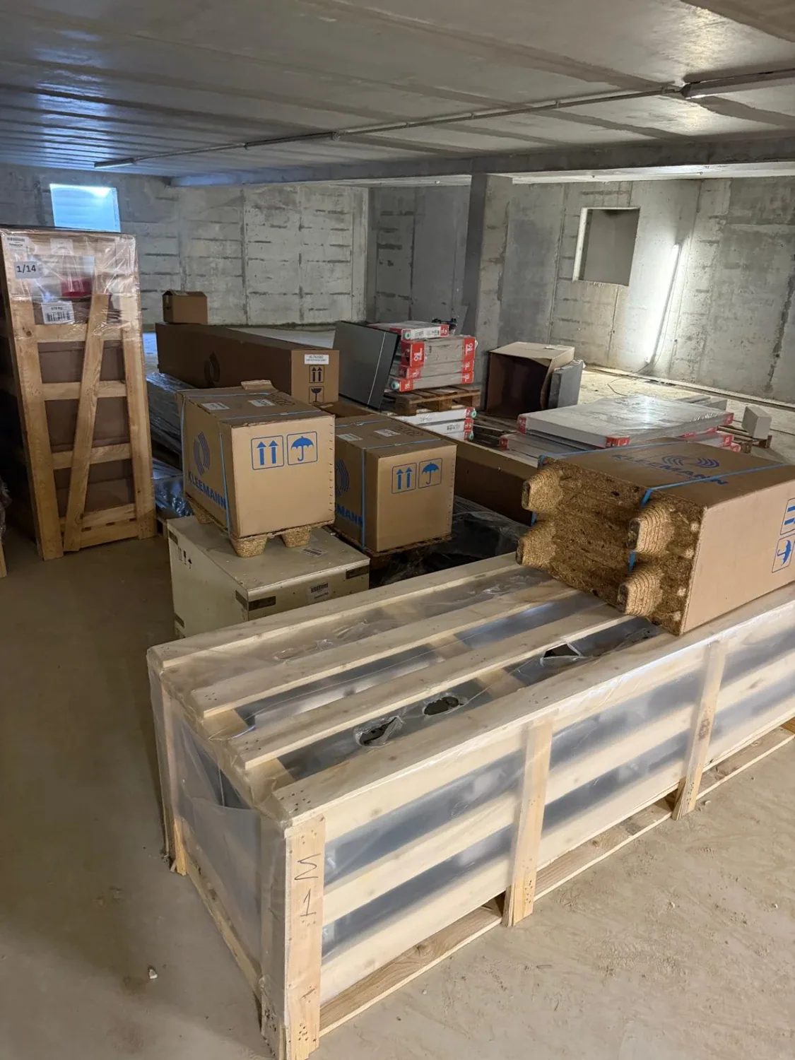 Holzkisten und Kartons mit Aufzugsbauteilen im Materiallager vor der Montage